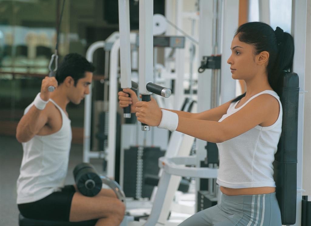 The Oberoi Bengaluru Hotel Exterior photo A woman using a lat pulldown machine